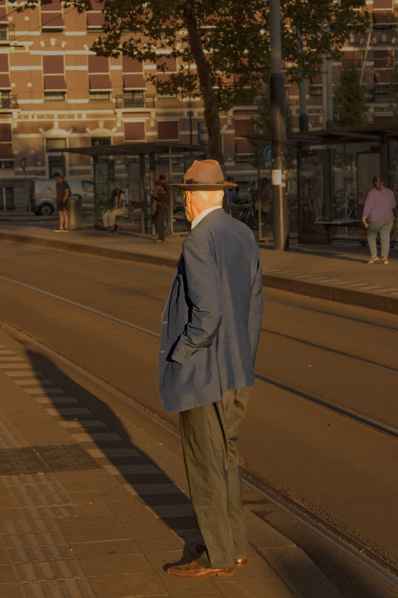 a timelessly dressed older gentleman awaits his tram in Amsterdam, NL