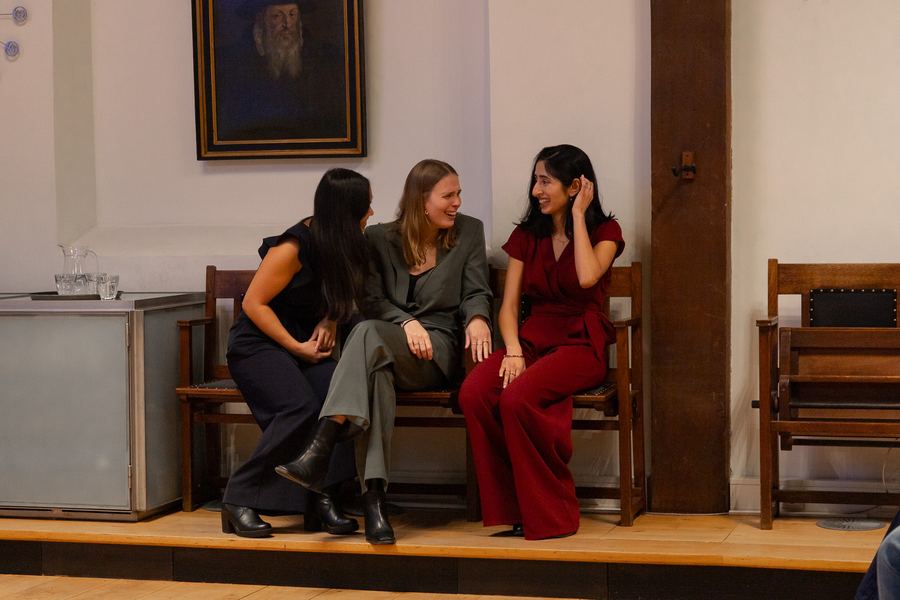 Three women laughing together on a bench beside the stage