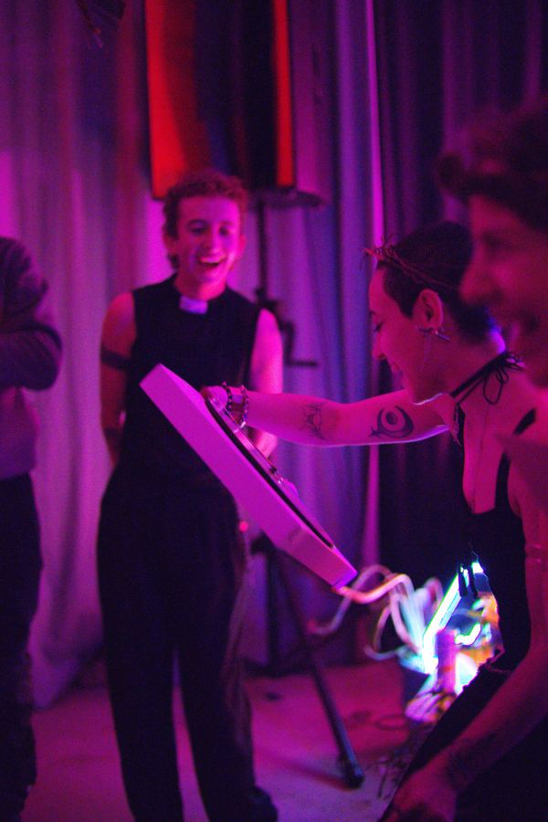 Guests laughing around a DJ controller in purple light